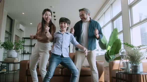 Happiness cheerful asian family dad mom and son funny dancing in living room