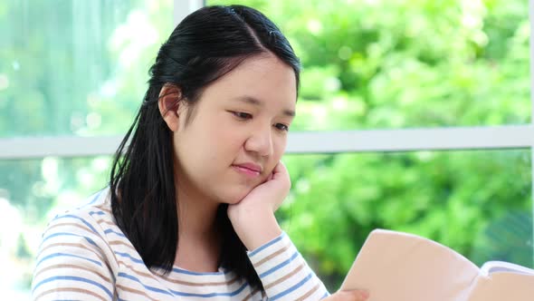 Asian Girl Reading A Book In Living Room