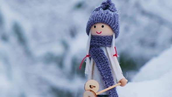 Angel Gnome in Scarf and Knitted Hat Skiing on Snowy Fir Branch Elf Toy on Skis in Snowy Landscape