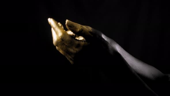 Closeup of the Black Hands of a Woman with Golden Fingers on a Black Background