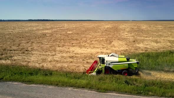 Harvester Moves Along Farmland Cutting Off Ripe Grain