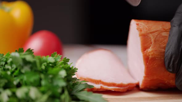 Slicing Traditional Ham Into Pieces on a Wooden Cutting Board with a Knife