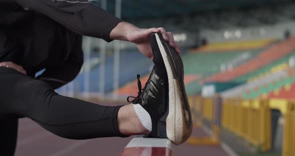 Athlete Stretching Before Training on Stadium