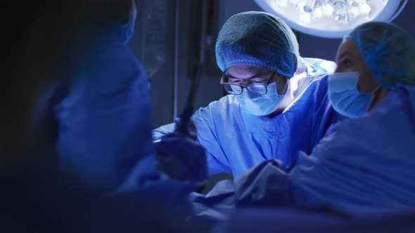 Diverse surgeons wearing face masks and protective clothing in operating theatre