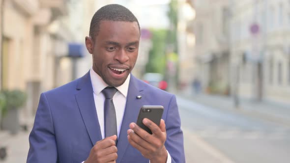 Outdoor African Businessman Celebrating on Smartphone