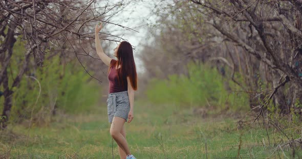 Young Pretty Woman Walks Through a Tree Garden