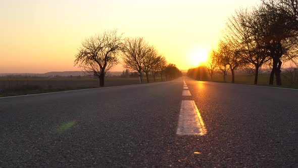 A Deserted Highway Leads Toward the Golden Sunset in a Rural Area  View From the Middle of the Road