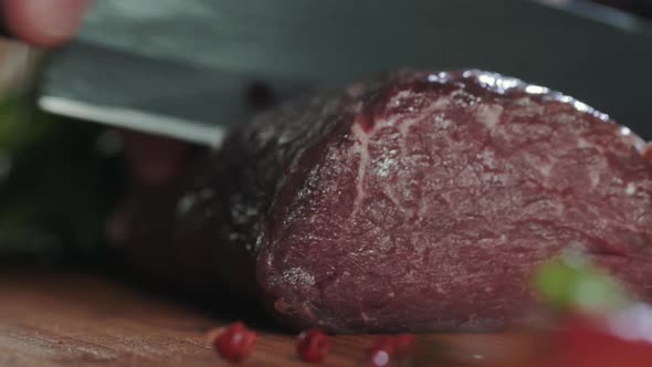 Cook cuts raw meat with a knife for cooking filet mignon on the grill