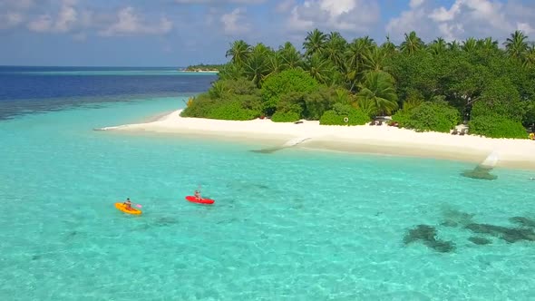 Aerial drone view of a man and woman couple kayaking around a tropical island