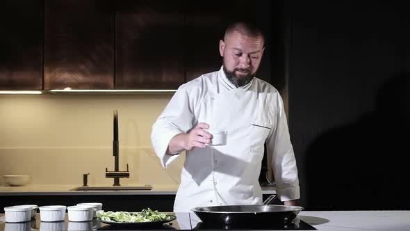 Cook man pours brown soy sauce into wok pan to cook delicious dish.