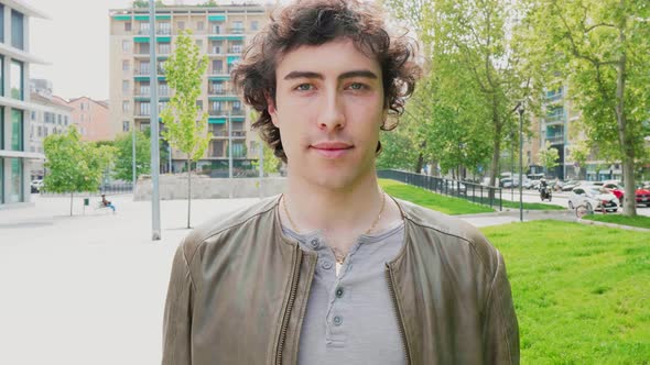 Young man standing in the city, looking at camera