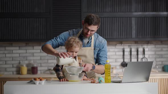 Father and Little Son are Sifting Flour for Pancake Batter Cooking Together at Home Kitchen at