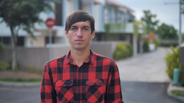 Portrait of Handsome Caucasian Man in Red Plaid Shirt Standing in Front of the Camera and Smiling at