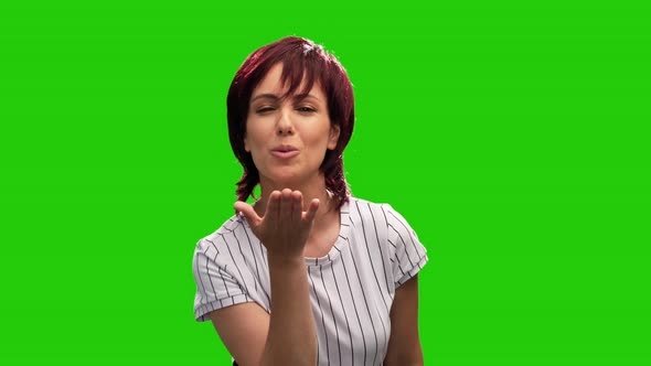 Beautiful female model posing on green screen blows kiss and shows thumb up gesture