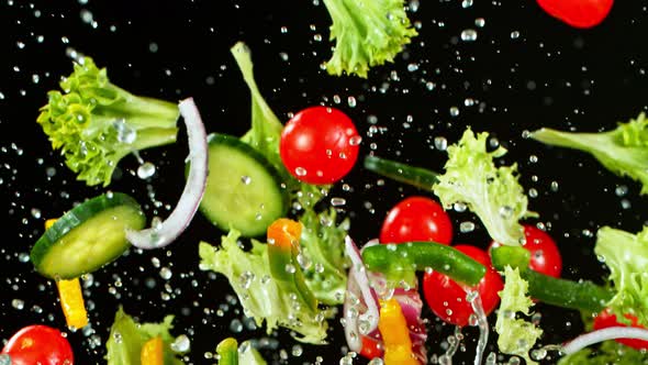 Super Slow Motion Shot of Flying Fresh Vegetables and Water Splash on Black Background at 1000Fps