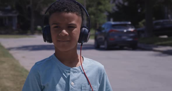 Young African american kid close up listening to music outdoors on headphones