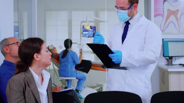 Doctor Taking Notes on Clipboard About Patient Dental Problems