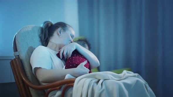 Mother Sitting in a Rocking Chair with Her Little Baby