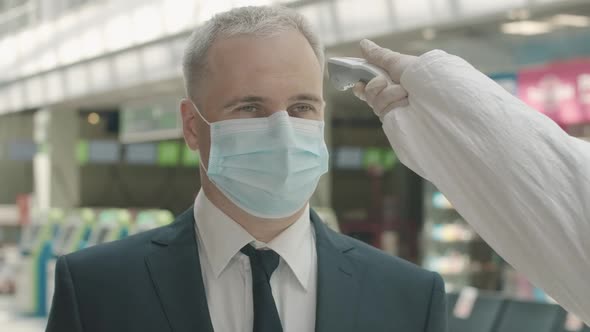 Close-up Portrait of Mid-adult Businessman in Face Mask Standing in Airport Departure Area As