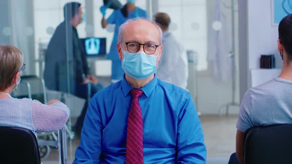 Senior Man Looking at Camera in Hospital Waiting Area