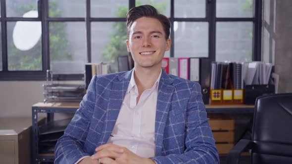 Close up portrait young businessman smiling to camera in office