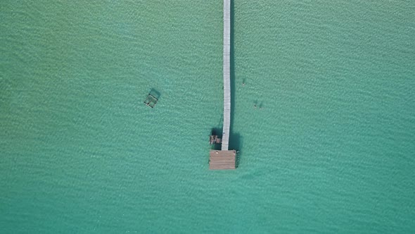 Aerial of a long wooden pier in the middle of the ocean