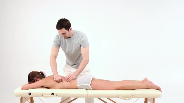 Male masseur doing therapeutic back massage for a woman