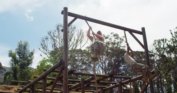 Military soldiers climbing rope during obstacle course