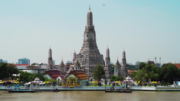panning shot of Wat Arun Temple with Chao Phraya river in Bangkok, Thailand