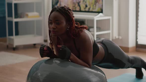 African Slim Woman Streching Abdomincal Muscle While Sitting on Yoga Swiss Ball