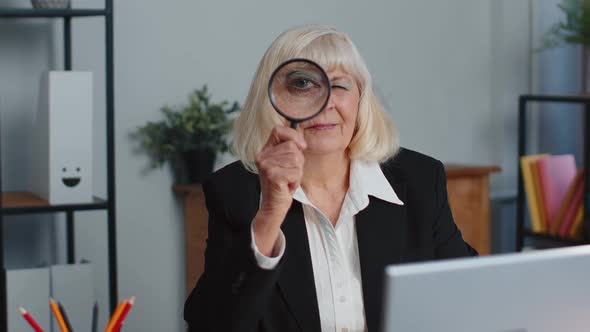 Senior Business Woman Looks Through a Magnifying Glass Investigate Examine Analyzing Reading