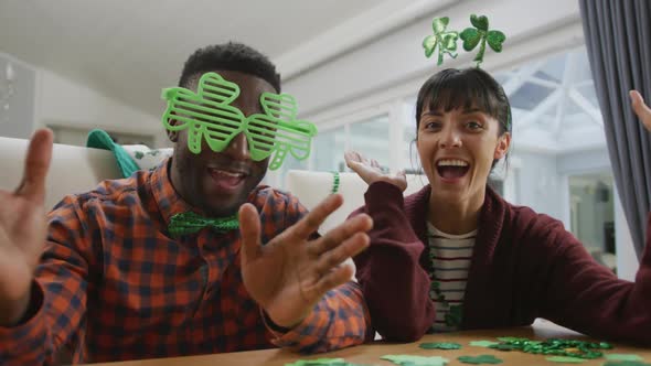 Portrait of happy diverse couple wearing clover shape items and having video call