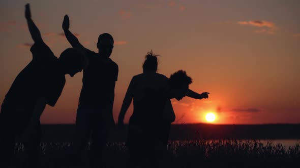 Silhouettes of Young People Have Fun at Sunset