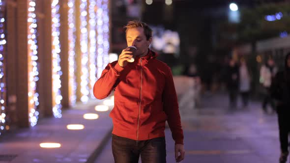 Man Drinking Takeaway Coffee in a Night City