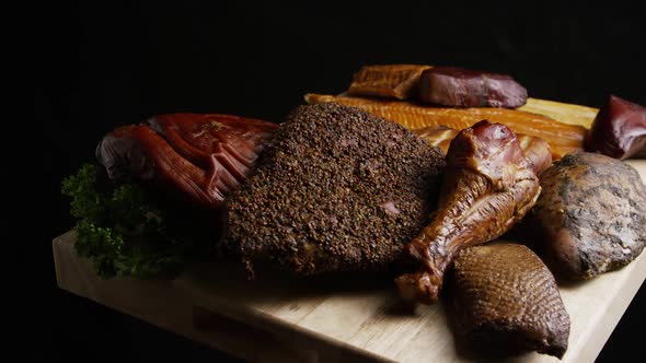 Rotating shot of a variety of delicious, premium smoked meats on a wooden cutting board 