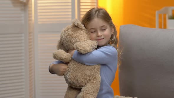 Sweet Curly Preschool Girl Hugging Teddy Bear and Smiling