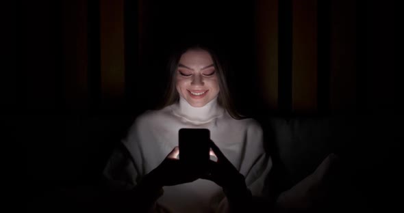 Young Female Lying on the Bed and Uses Smartphone Types Text Night Time Online Communication