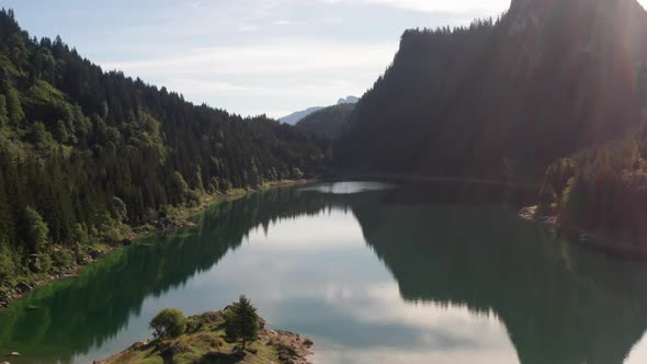 Flying over Peaceful lake surrounded by mountains in summer