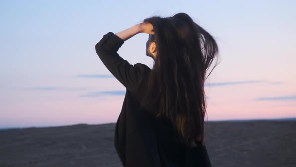 Portrait of Charming Woman Looking at Camera in Slow Motion Against Background of Sunrise or Sunset