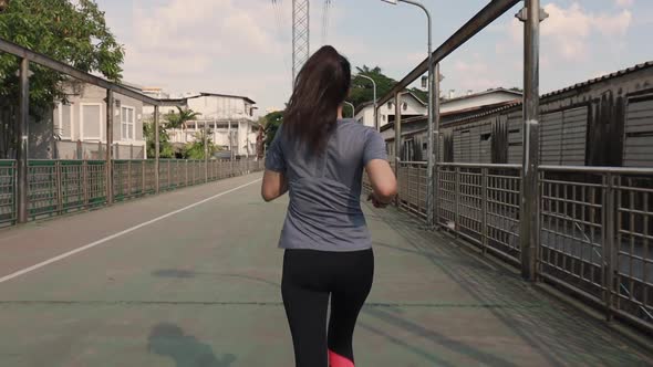 Attractive young Asian woman athlete running in the city.
