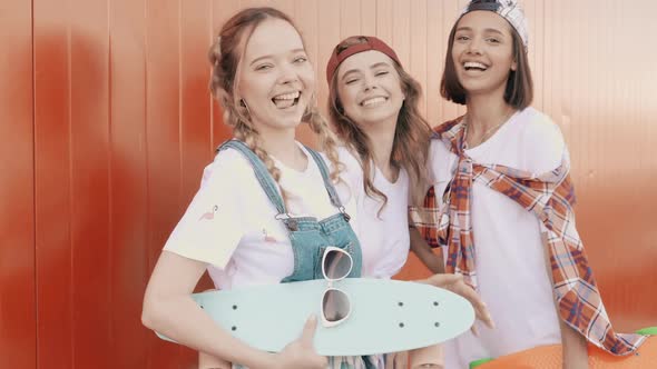 Three young smiling beautiful female with colorful penny skateboards