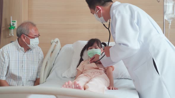 Asian doctor measure heart rate by stethoscope on young little kid patient on bed in recovery room.