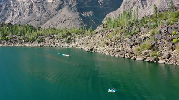 aerial drone tourists in the mountain forest of Skardu Pakistan taking a motor boat ride on beautifu
