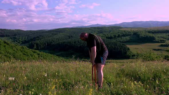 Man training outdoors. Sunset, over green hill