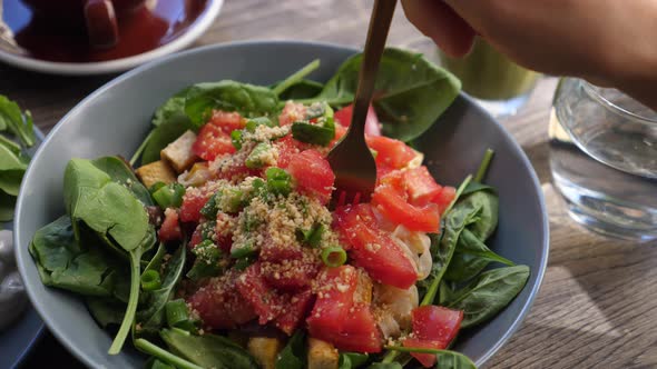 Close Up of Fork Picking Up Noodles From Colorful Warm Salad Bowl with Spinach and Tomato. Healthy