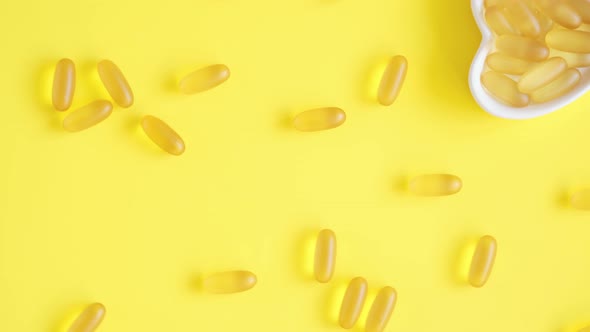 Vitamin D and Omega 3 Fish Oil Capsules Supplement in a Heartshaped Plate on Yellow Background