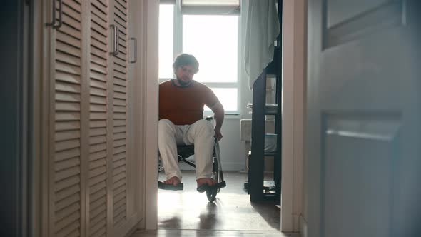 Man in a Wheelchair Passing the Hallway in His Apartment