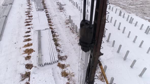 Close-up aerial drone view of a pile bore machine at work at winter construction site 24