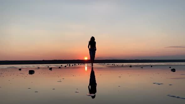 Silhouette of a beautiful woman dancing in the background of the sunset in the water.