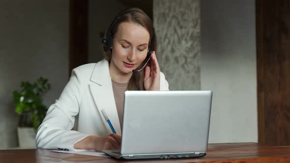 An Attractive Employee in a White Jacket is Sitting at Her Desk Holding a Video Conference with